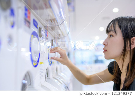Young woman spinning a capsule toy, Gacha 121249377