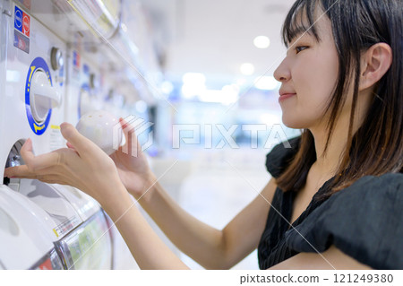 Young woman spinning a capsule toy, Gacha 121249380
