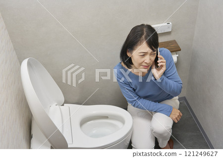 一名女子在浴室裡打電話給修理工 121249627