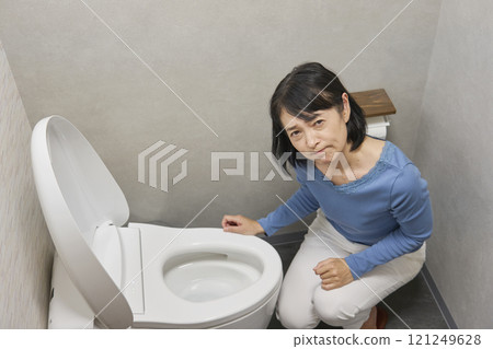 Woman troubled by toilet malfunction, looking at camera 121249628