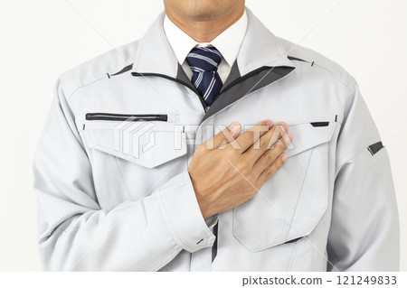 A man wearing work clothes and holding his hand on his chest, white background A man wearing work clothes and holding his hand on his chest, white background 121249833