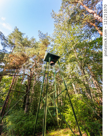 A tall and impressive bell tower rises majestically amidst a sea of vibrant trees in a serene forest setting 121251070