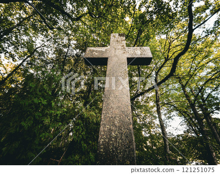 A weathered stone cross stands among vibrant trees, evoking tranquility and deep peaceful reflection A weathered stone cross stands among vibrant trees, evoking tranquility and deep peaceful reflection 121251075
