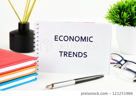 Notebook on economic trends placed alongside colorful stationery and a potted plant on a desk 121251966
