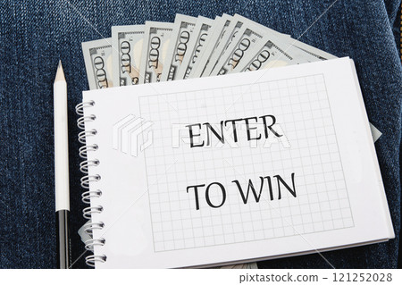 The concept of technology and development. Phrase, word, text ENTER TO WIN on a blank sheet of notepad against the background of dollar bills The concept of technology and development. Phrase, word, text ENTER TO WIN on a blank sheet of notepad against the background of dollar bills 121252028