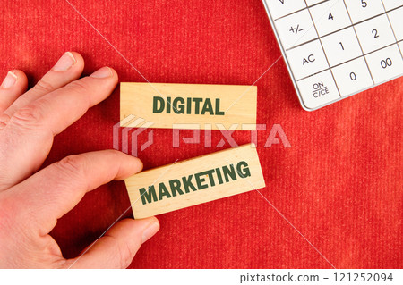 Explore effective strategies for digital marketing with wooden blocks on a red surface next to a calculator Explore effective strategies for digital marketing with wooden blocks on a red surface next to a calculator 121252094