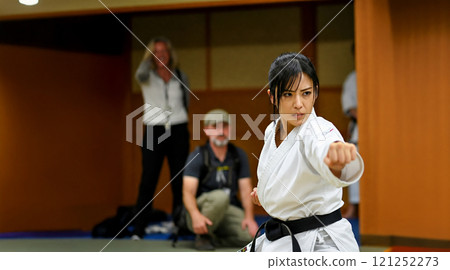 A Japanese woman demonstrating karate skills in front of foreign observers at a karate dojo 121252273