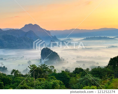 Stunning sunrise over misty mountains with layers of fog blanketing the valley. Serene landscape view featuring green forest, hills, and warm morning light, perfect for nature and travel themes Stunning sunrise over misty mountains with layers of fog blanketing the valley. Serene landscape view featuring green forest, hills, and warm morning light, perfect for nature and travel themes 121252274