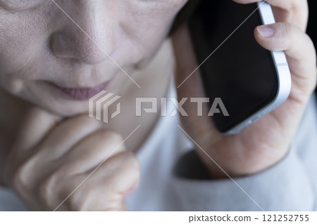 Elderly woman receiving a spoofed phone call on her smartphone 121252755