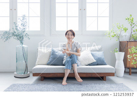 Woman sitting and relaxing on sofa Woman sitting and relaxing on sofa 121253937