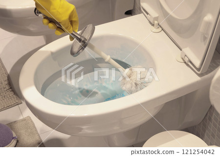 Woman in yellow rubber gloves scrub toilet bowl with brush and cleaner. House cleaning. Interior of house. Woman in yellow rubber gloves scrub toilet bowl with brush and cleaner. House cleaning. Interior of house. 121254042