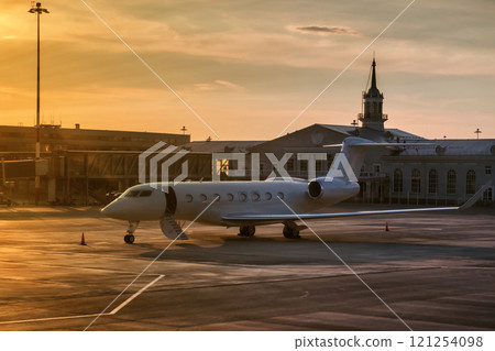 Business plane with the door open by a ladder in the golden evening light on the airport apron near the terminal 121254098
