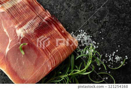 Sliced prosciutto and rosemary on a stone table. Sliced prosciutto and rosemary on a stone table. 121254168