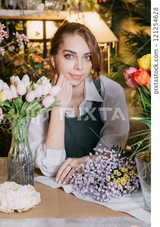 A woman in her florist shop collects bouquets of flowers. The concept of a small business. Bouquets of tulips for the holiday on March 8. A woman in her florist shop collects bouquets of flowers. The concept of a small business. Bouquets of tulips for the holiday on March 8. 121254628