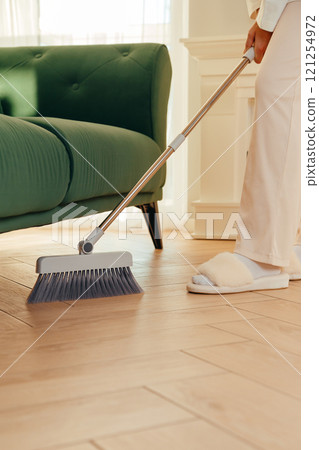 Dry cleaning the floor under furniture with a long-handled brush Dry cleaning the floor under furniture with a long-handled brush 121254972