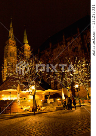 Illuminated Nuremberg at night. Illuminated church of St. Sebald and sidewalk cafe with trees. Old town of Nuremberg at night. Medieval street in the evening. Ancient cathedral in Christmas lights. 121255331