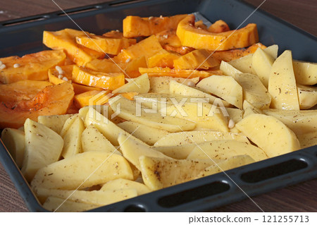Sliced potatoes and pumpkin with pine nuts and spices on baking tray. Raw vegetables for baking. Healthy food in kitchen at home. Natural farm local products. Sliced potatoes and pumpkin with pine nuts and spices on baking tray. Raw vegetables for baking. Healthy food in kitchen at home. Natural farm local products. 121255713