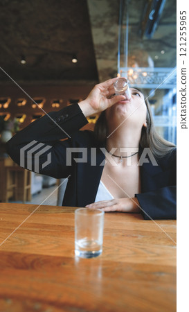 A woman clinks glasses and drinks an alcoholic tincture - close-up 121255965