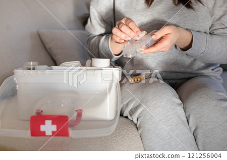 Closeup female hand neatly placing medicament at domestic first aid kit top view. 121256904