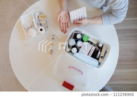 Female hands hold a pink round pill. The woman is going to take medicine for headaches, stomach pain 121256908
