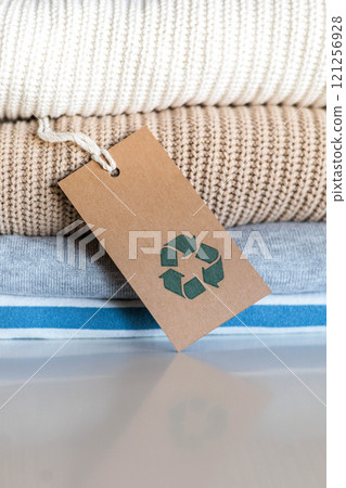 Knitted warm clothes neatly folded heap with craft tag recycling material circle arrow closeup 121256928