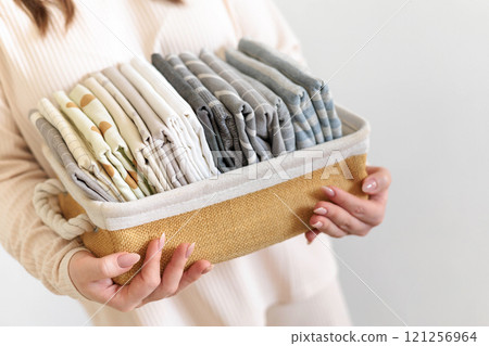 Female hands close up hold wicker stylish natural basket with pillowcases and bed linen. Female hands close up hold wicker stylish natural basket with pillowcases and bed linen. 121256964