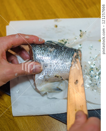 Close-up of a person removing scales from a salmon fillet with a knife. High quality photo Close-up of a person removing scales from a salmon fillet with a knife. High quality photo 121257666