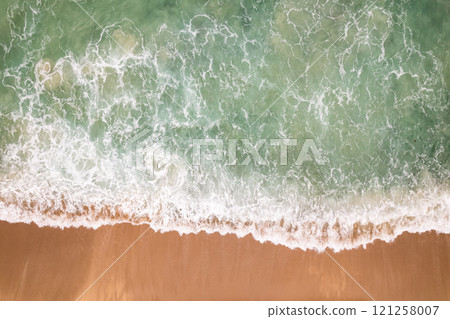 Top view beach with waves crashing on sandy shore,Beautiful waves sea surface in summer seascape background,Amazing beach colorful water background Top view beach with waves crashing on sandy shore,Beautiful waves sea surface in summer seascape background,Amazing beach colorful water background 121258007