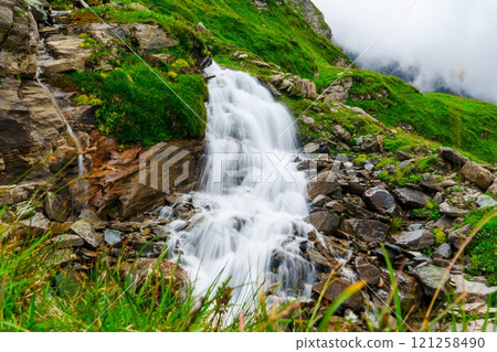 Majestic Mountain Waterfall Flowing into a Serene Pool Surrounded by Lush Greenery 121258490