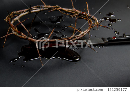 A crown of thorns with blood and knife on a dark background. Conceptual photo to use in the design. A wreath of branches with thorns with blood 121259177