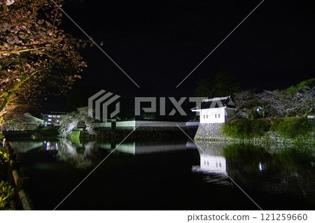 The horse-shed at night, the castle tower, and the castle walls reflected in the moat 121259660