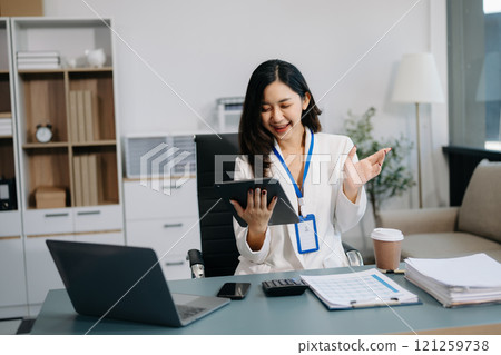 Asian Businesswoman Analyzing Finance on Tablet and Laptop at modern Office Desk Asian Businesswoman Analyzing Finance on Tablet and Laptop at modern Office Desk 121259738