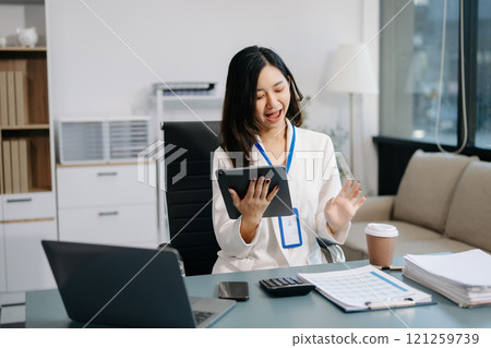 Asian Businesswoman Analyzing Finance on Tablet and Laptop at modern Office Desk Asian Businesswoman Analyzing Finance on Tablet and Laptop at modern Office Desk 121259739