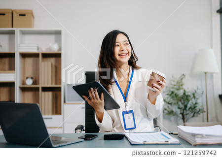 Asian Businesswoman Analyzing Finance on Tablet and Laptop at modern Office Desk Asian Businesswoman Analyzing Finance on Tablet and Laptop at modern Office Desk 121259742
