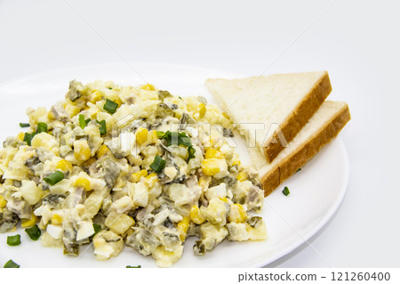 Ukrainian and Russian salad Olivier according to a new recipe on a white plate. Healthy salad Olivier with meat, corn and slices of white bread. Delicious and tasty salad on white plate. Ukrainian and Russian salad Olivier according to a new recipe on a white plate. Healthy salad Olivier with meat, corn and slices of white bread. Delicious and tasty salad on white plate. 121260400