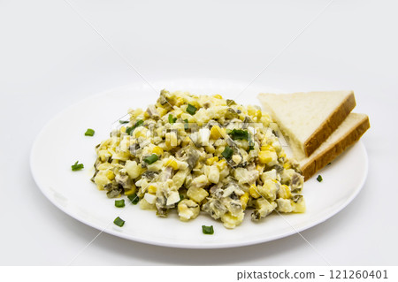 Ukrainian and Russian salad Olivier according to a new recipe on a white plate. Healthy salad Olivier with meat, corn and slices of white bread. Delicious and tasty salad on white plate. Ukrainian and Russian salad Olivier according to a new recipe on a white plate. Healthy salad Olivier with meat, corn and slices of white bread. Delicious and tasty salad on white plate. 121260401