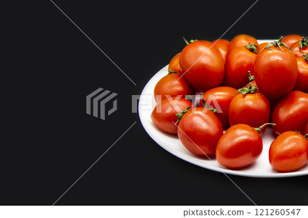 Ripe fresh red cherry tomatoes on a white plate against dark background. Beautiful and healthy fresh cherry tomatoes without GMO. Copy space for text or design Ripe fresh red cherry tomatoes on a white plate against dark background. Beautiful and healthy fresh cherry tomatoes without GMO. Copy space for text or design 121260547