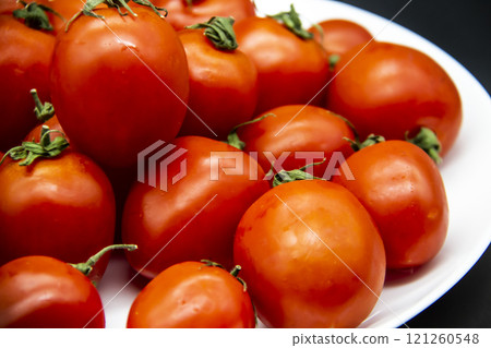 Ripe fresh red cherry tomatoes on a white plate against dark background.  Beautiful and healthy fresh cherry tomatoes without GMO. 121260548