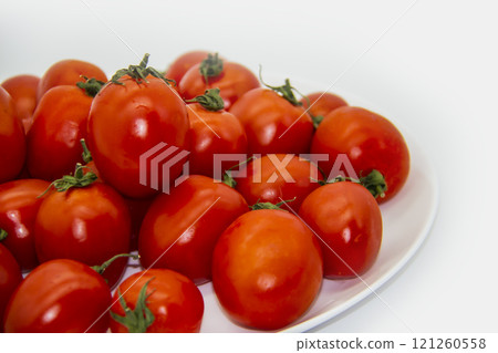 Ripe fresh red cherry tomatoes on a white plate against white background. Beautiful and healthy fresh cherry tomatoes without GMO. Ripe fresh red cherry tomatoes on a white plate against white background. Beautiful and healthy fresh cherry tomatoes without GMO. 121260558