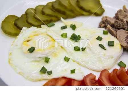 Delicious fresh tuna with eggs, tomatoes, cucmbers with green onion at the morning. Healthy and diet breakfast with tuna, eggs and vegetables on the white plate against white background Delicious fresh tuna with eggs, tomatoes, cucmbers with green onion at the morning. Healthy and diet breakfast with tuna, eggs and vegetables on the white plate against white background 121260601