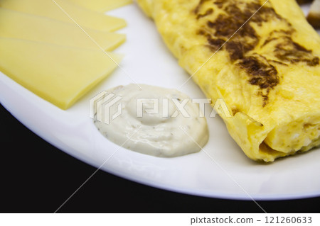 Amazing breakfast with tasty omelet, tomatoes, cheese, bread and sauce on the white plate. Delicious omelet made like rolle, other ingredients. Tasty and diet food. Healthy meal for breakfast or lunch 121260633