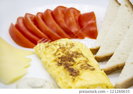 Amazing breakfast with tasty omelet, tomatoes, cheese, bread and sauce on the white plate. Delicious omelet made like rolle, other ingredients. Tasty and diet food. Healthy meal for breakfast or lunch 121260635