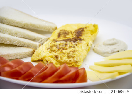 Amazing breakfast with tasty omelet, tomatoes, cheese, bread and sauce on the white plate. Delicious omelet made like rolle, other ingredients. Tasty and diet food. Healthy meal for breakfast or lunch 121260639