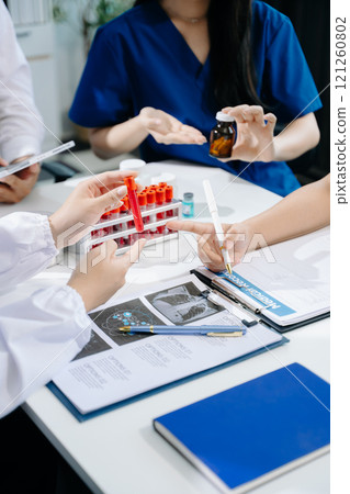 Medical team having a meeting with doctors in white lab coats and surgical scrubs seated 121260802