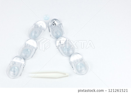 A Christmas tree made of containers with contact lenses lies on a white background, a lying lens is visible on top, and lens tweezers with space for text are at the bottom. High quality photo A Christmas tree made of containers with contact lenses lies on a white background, a lying lens is visible on top, and lens tweezers with space for text are at the bottom. High quality photo 121261521