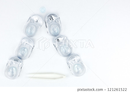 A Christmas tree made of containers with contact lenses lies on a white background, a lying lens is visible on top, at the bottom there are tweezers for lenses with space for text view from above A Christmas tree made of containers with contact lenses lies on a white background, a lying lens is visible on top, at the bottom there are tweezers for lenses with space for text view from above 121261522