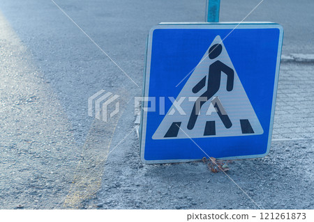 Blue warning road sign Pedestrian crossing that has loosened and slid down a supporting metal pole to the ground. Need for maintenance and monitoring of the condition of road facilities Blue warning road sign Pedestrian crossing that has loosened and slid down a supporting metal pole to the ground. Need for maintenance and monitoring of the condition of road facilities 121261873