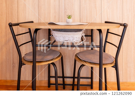 Modern chairs at small dining table, wooden wall Modern chairs at small dining table, wooden wall 121262090
