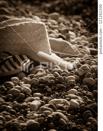 Sun hat and flip flops on stone beach 121262200