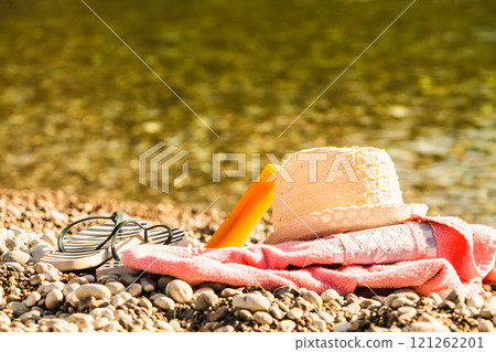 Sun hat and flip flops on stone beach 121262201